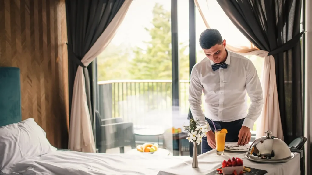 Hotelmitarbeiter serviert ein alkoholfreies Getränk im Room Service – ein Beispiel für moderne Zero-Proof-Angebote in Hotels.