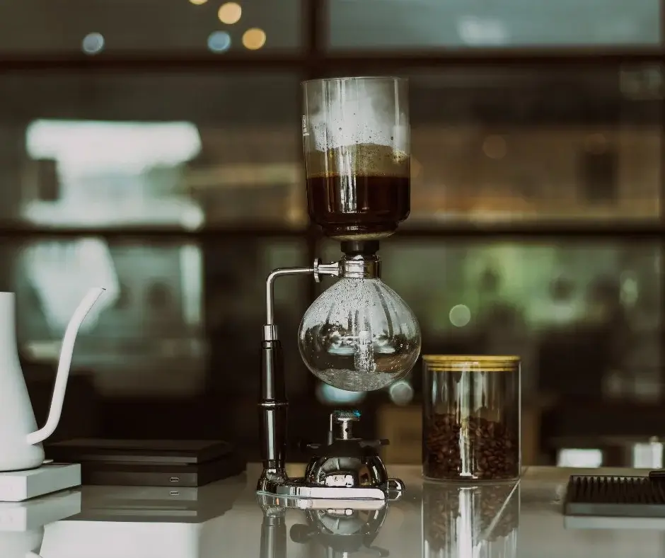 A glass extraction vessel on a countertop, with a blurred interior in the background.