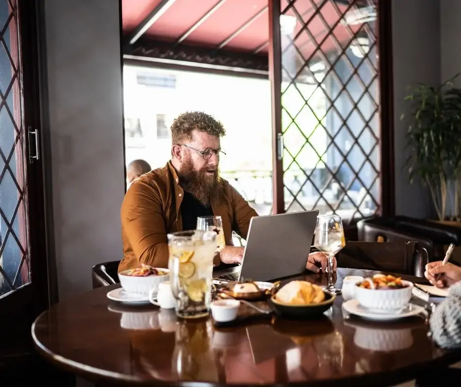 Restaurantgast arbeitet tagsüber am Laptop und bestellt alkoholfreie Zero-Proof-Getränke als Teil eines modernen Gastronomiekonzepts