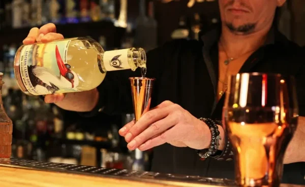 Bartender pouring alcohol-free Volante Free Spirits gin into a shaker to prepare a cocktail.
